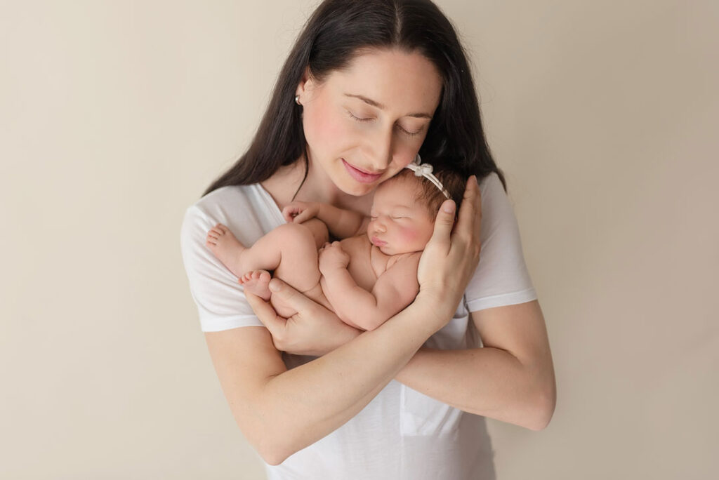 mama haelt ihr neugeborenes baby in den armen im fotostudio wien von michaela krasnanska