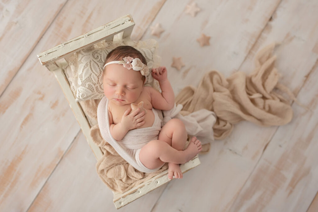 6 Tage altes baby im Fotostudio liegt im Bett und schlaeft